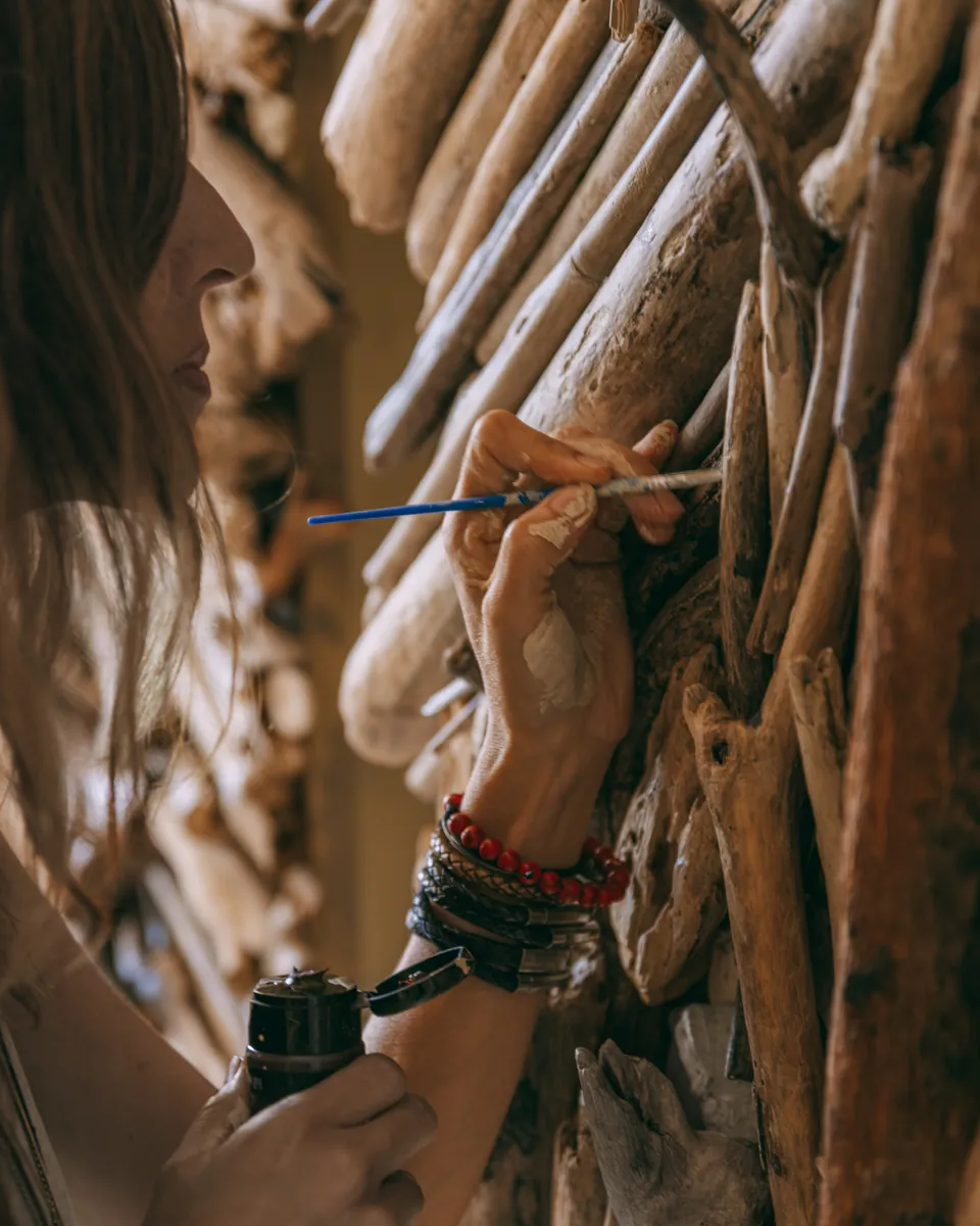 Hands detailing a piece of driftwood with a fine brush